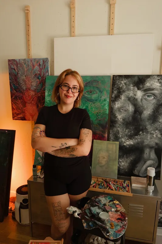 Merve Heper in her studio, in front of her paintings